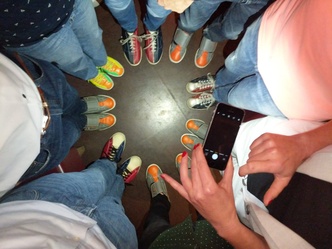 Blick von oben auf einen Kreis von Personen ab der Hüfte bis zu den Füßen auf dem alle Bowlingschuhe tragen